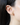 Close-up of a 14k gold drop earring featuring a pear-cut green peridot and diamond-set serpent charm worn on the ear.