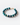 A detailed angled shot of the beaded bracelet highlighting the smooth, round Shattuckite beads in a mix of oceanic blue, turquoise, and forest green hues. At the center is a 14k gold rondelle set with nine sparkling natural diamonds, flanked by tiny faceted gold spacers. The bracelet closes with a classic 14k gold toggle clasp and is arranged in a gentle curve on a clean white surface, emphasizing its artisanal quality and luxurious finish.