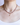 A close-up of a woman wearing the Stardust Necklace in Red Garnet, with a luminous baroque pearl pendant hanging from a diamond-set 14k gold bail, resting at the center of a strand of garnet and strawberry quartz beads. The model is dressed in a black top.
