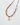 A close-up detail of the Stardust Necklace in Red Garnet, showcasing faceted garnet and strawberry quartz beads, spaced with tiny 14k gold beads and finished with a baroque freshwater pearl pendant hanging from a diamond-set 14k gold bail, laid on a white ceramic surface.